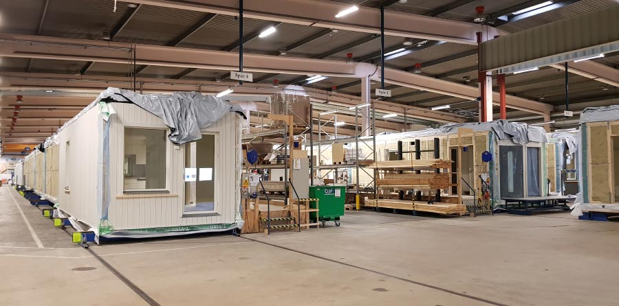 Prefabricated housing units being assembled in a factory space